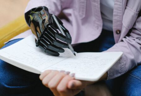 Artificial Intelligence, Education - Woman with modern prosthesis of hand writing in notebook