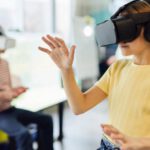 Wearable Technologies, Future Education - Young female in VR glasses standing in light room and testing new device