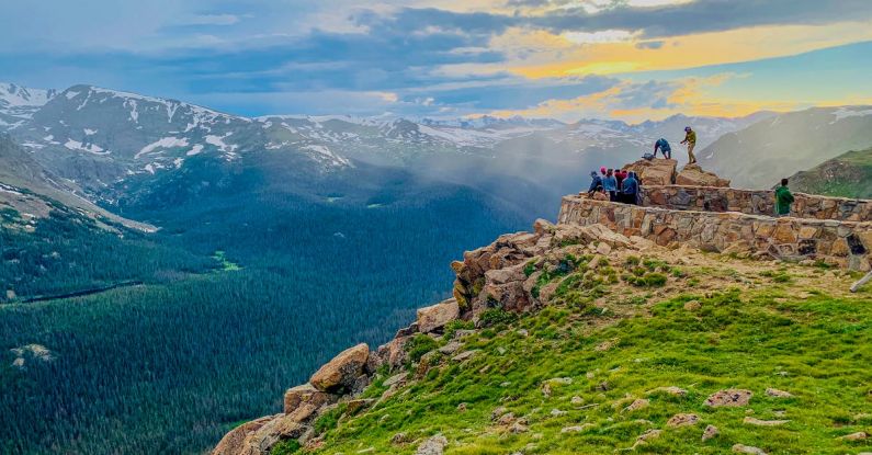 Reflection, Journey To Success - Anonymous travelers standing on stony observation point in Forest Canyon of Rocky Mountain National Park and admiring breathtaking view during sunset in Colorado